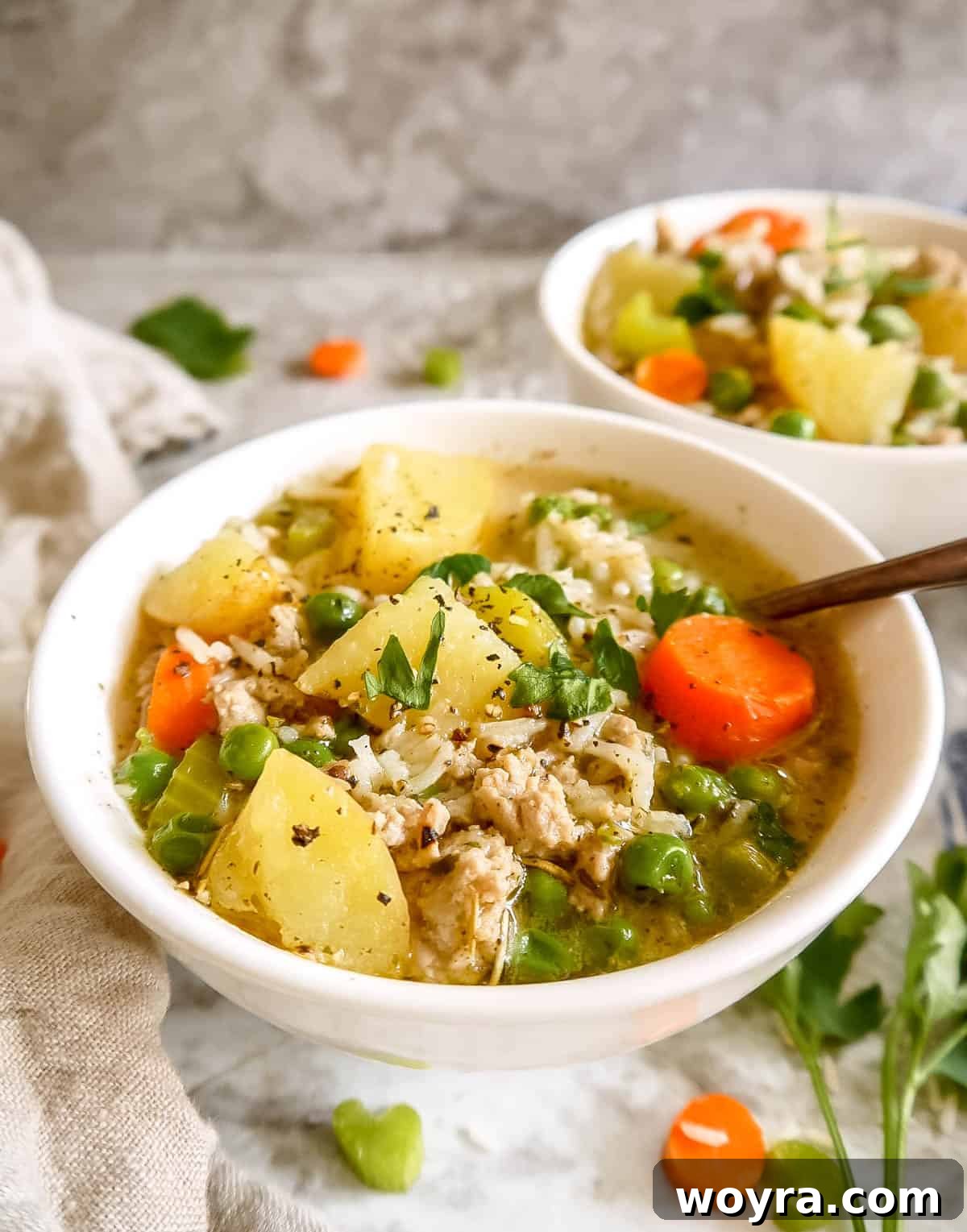 Ground turkey rice soup served in two rustic bowls with spoons, ready for a cozy meal.