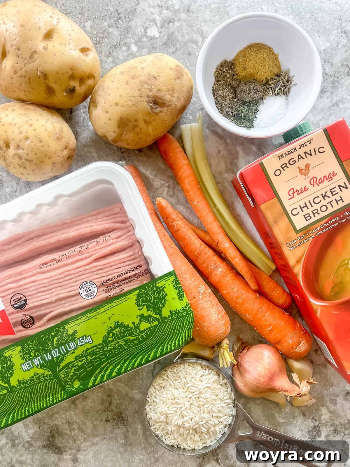Various fresh ingredients, including ground turkey, carrots, potatoes, and herbs, neatly laid out on a clean surface, ready for cooking.