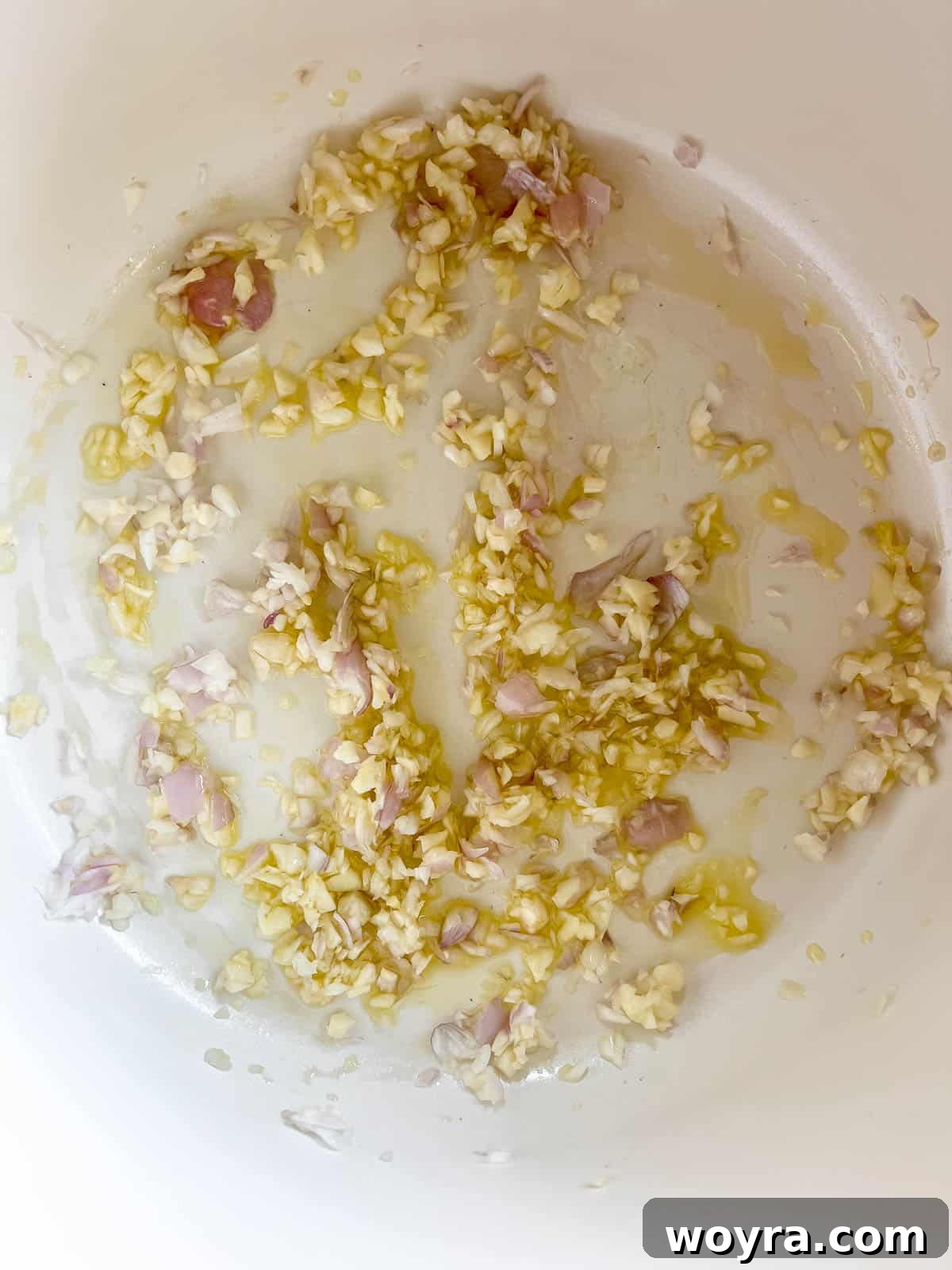 Sautéing minced shallot and garlic in olive oil in a large soup pan.