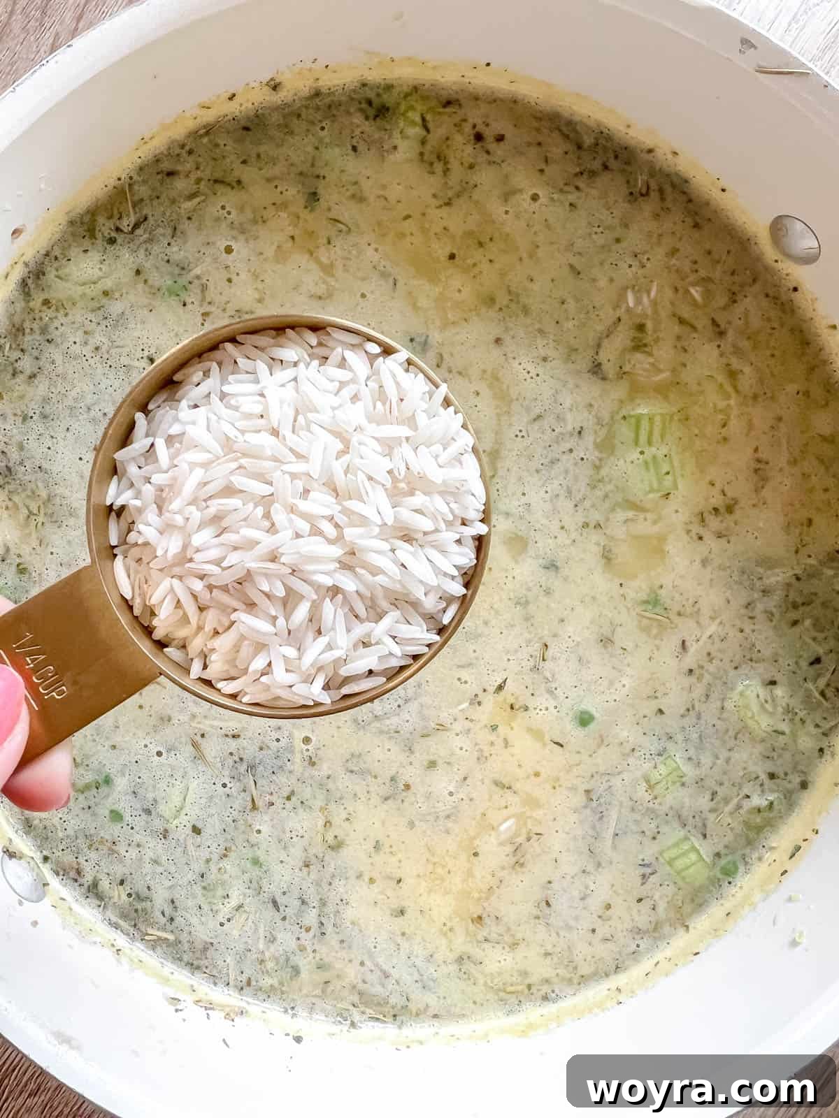 Adding white rice to the simmering ground turkey and vegetable soup for final cooking.