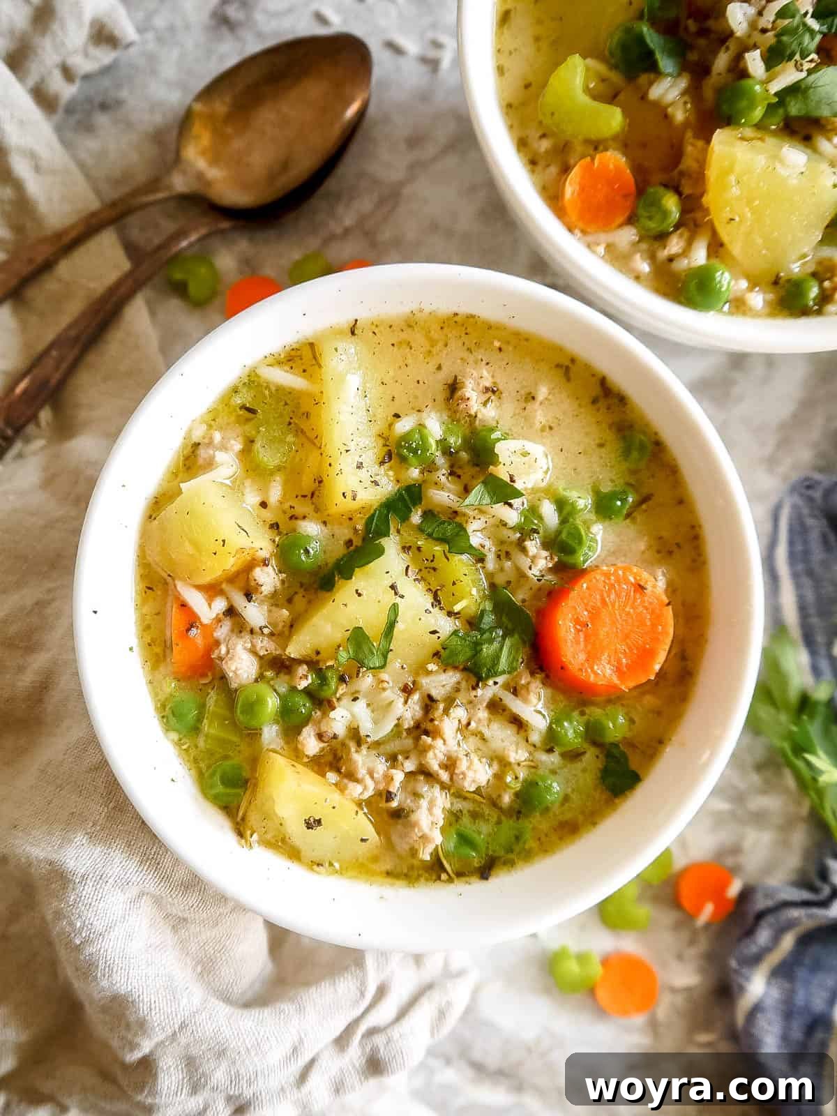 Creamy turkey rice soup garnished with fresh herbs, served in two elegant bowls, highlighting its texture and color.