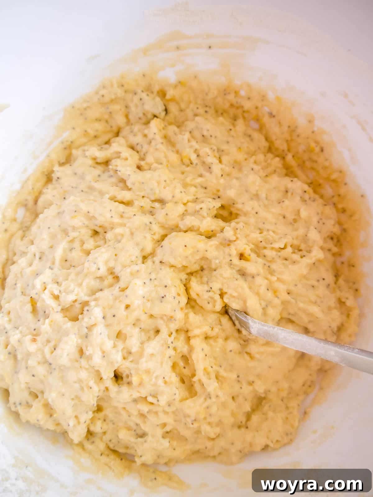 Mixing the wet ingredients for the Lemon Poppy Seed Coffee Cake batter in a large bowl, showing olive oil, brown sugar, egg, and lemon zest.