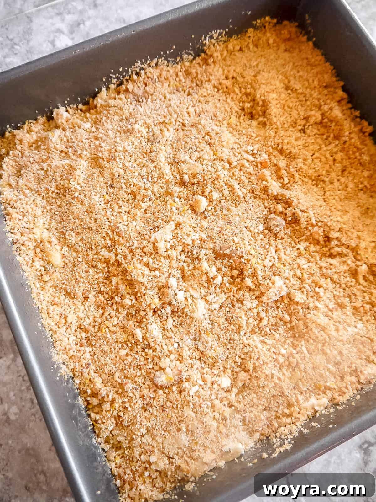 Unbaked Lemon Poppy Seed Coffee Cake with crumb topping generously sprinkled over the batter in a square baking pan.
