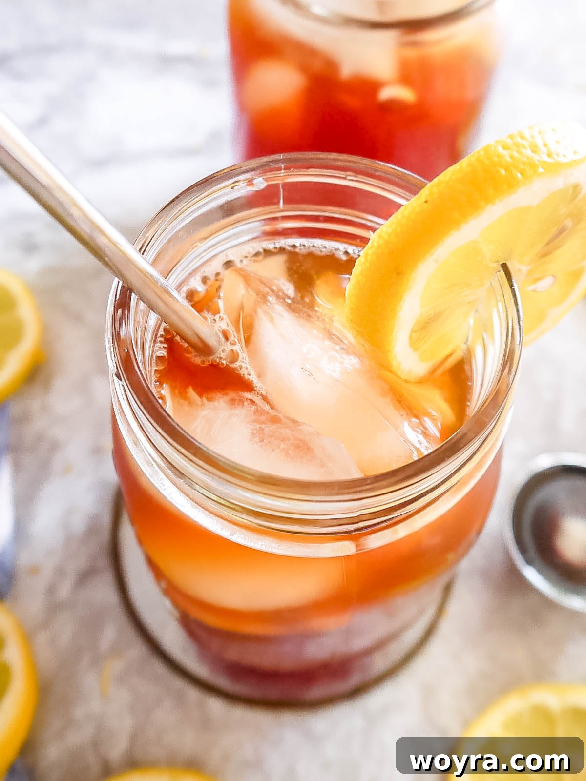 Sugar-free iced tea in a glass, garnished with a fresh lemon slice, on a light background.