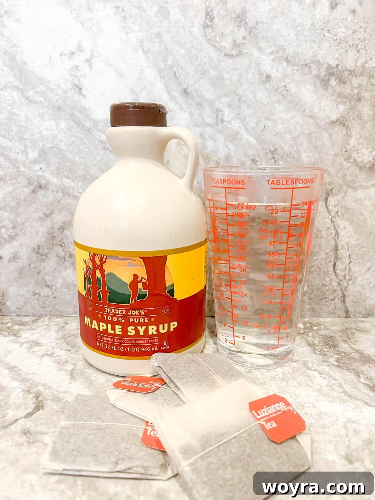 Ingredients laid out for making Maple Iced Tea: black tea bags, a pitcher of water, and a bottle of pure maple syrup.