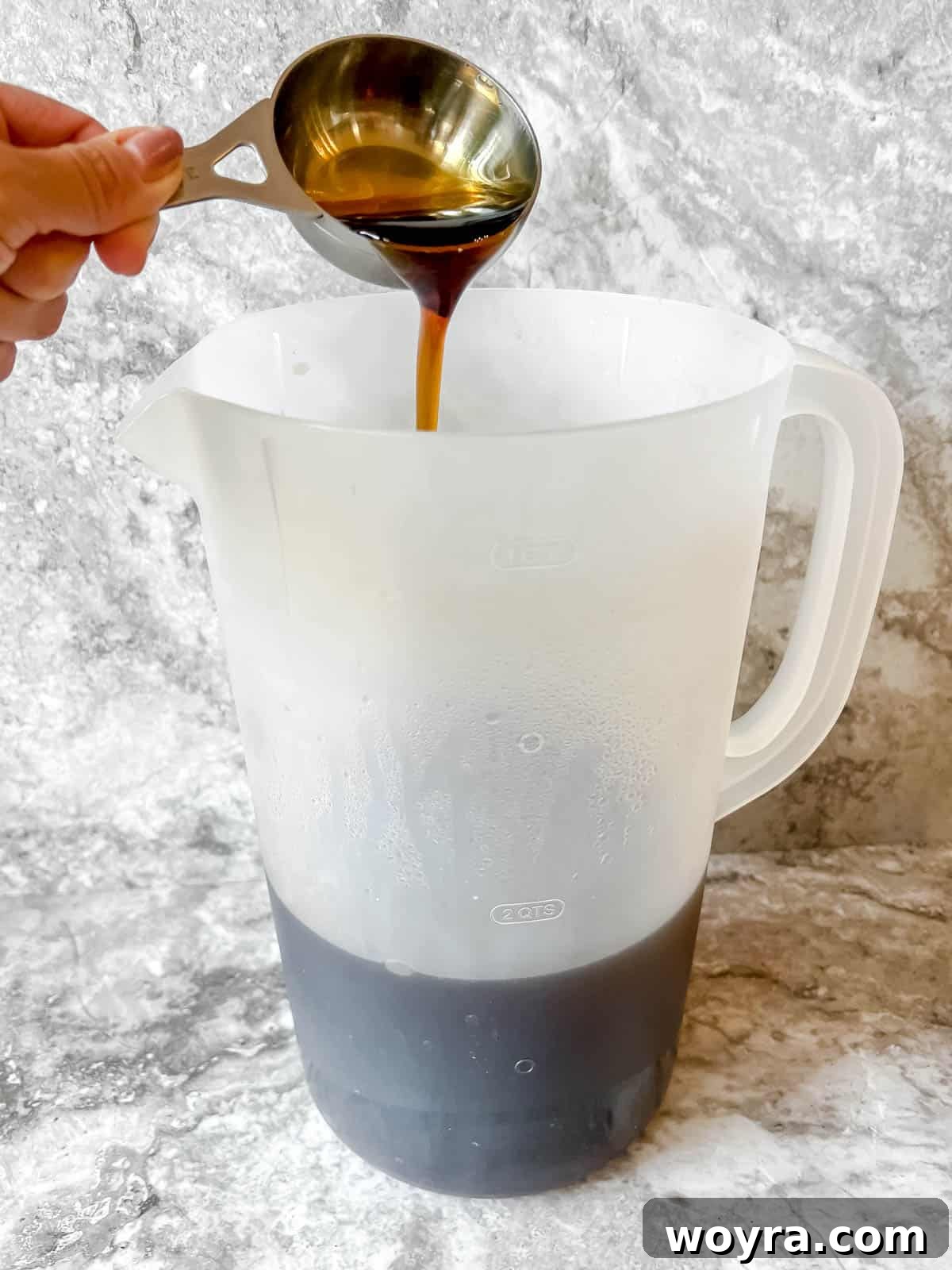 Pure maple syrup being added to the freshly steeped black tea concentrate.