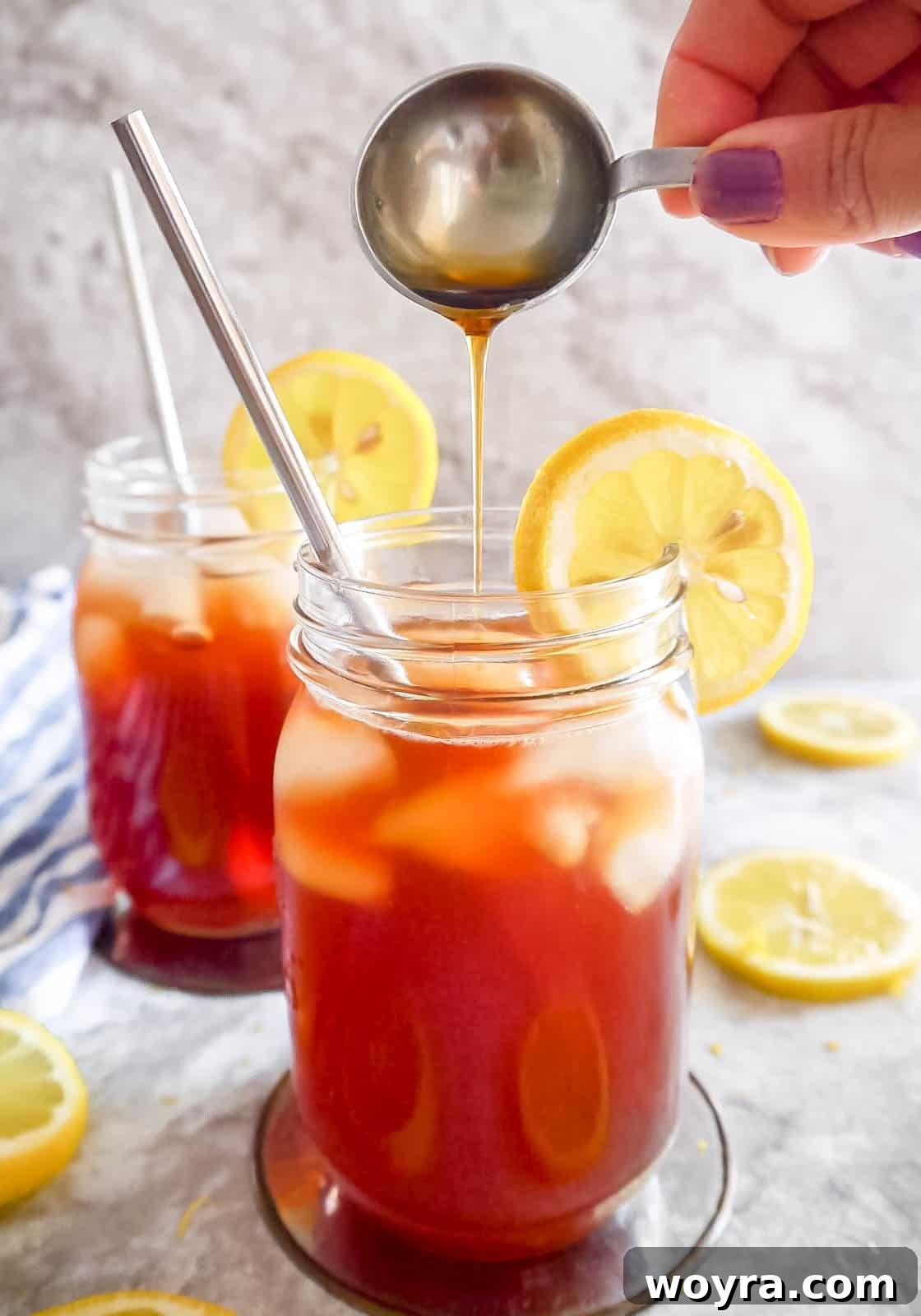 Healthy sweet tea in two elegant cups, with maple syrup being poured into one, highlighting the natural sweetness.