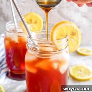 Maple syrup being poured into a glass of healthy sweet tea.