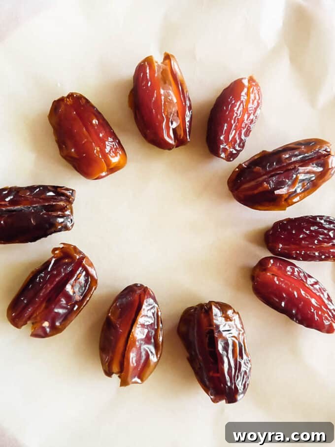 Pumpkin Spice & Chocolate Date Bites 6 Medjool dates on a plate, with one date carefully cut open to show the pit being removed, demonstrating the first step.