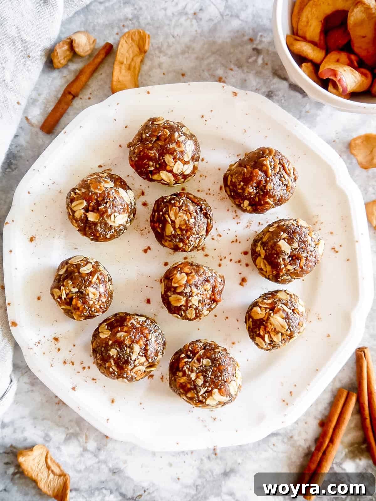 A close-up shot of homemade apple pie energy bites neatly arranged on a rustic plate, invitingly dusted with cinnamon.