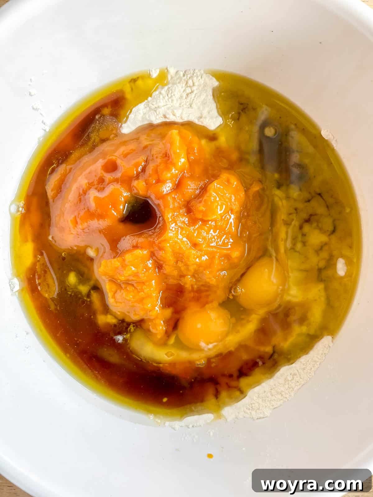 Pumpkin banana bread wet ingredients added into a well of dry ingredients in a bowl.