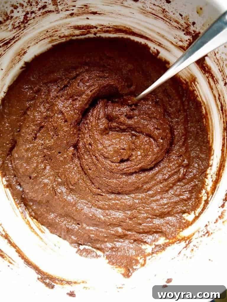 Paleo German Chocolate Cake 7 Wet ingredients for the Paleo German Chocolate Cake, including eggs, honey, and coconut oil, being mixed with an electric mixer.