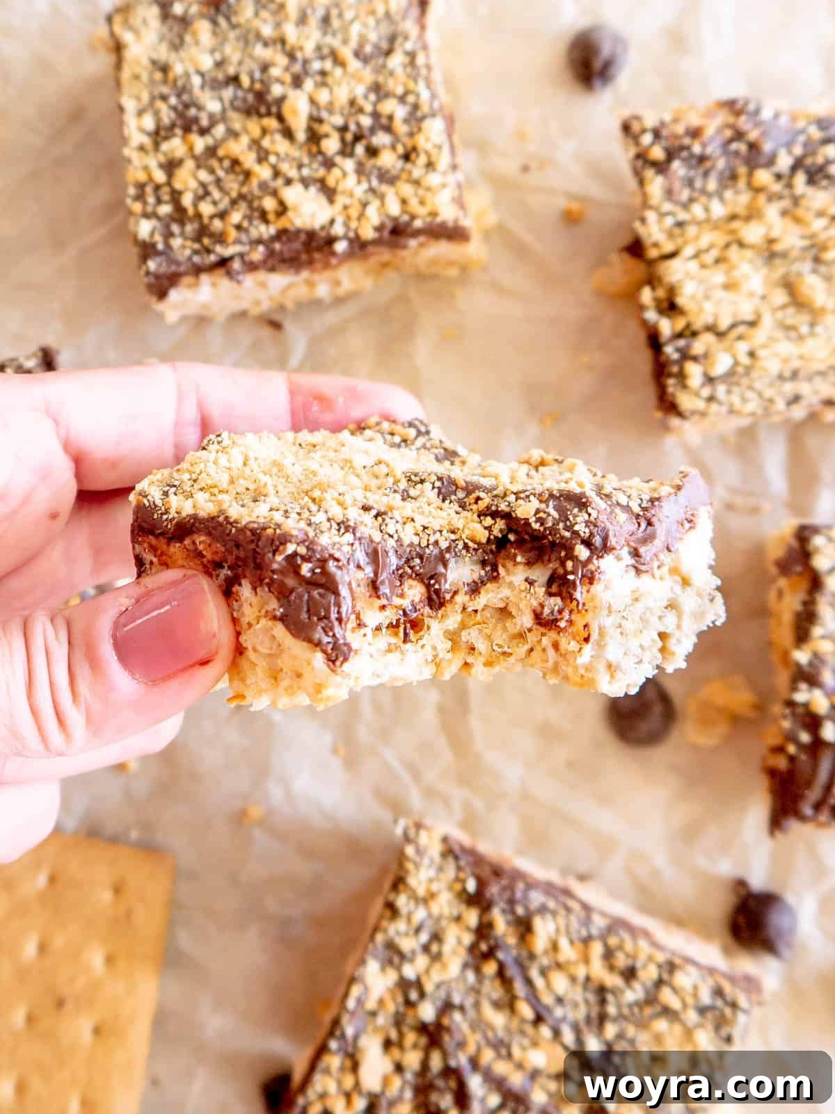 Campfire S'mores Krispie Bars 16 A S'mores Rice Krispie Treat with a bite taken out, revealing its delightful layers of crispy cereal, gooey marshmallow, and rich chocolate.