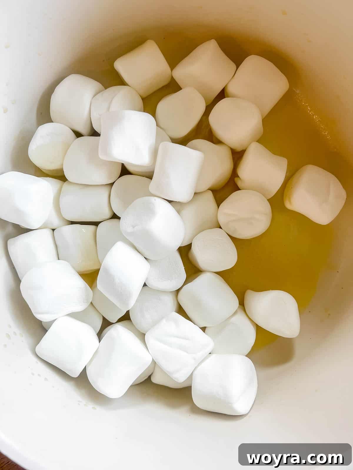 Campfire S'mores Krispie Bars 7 Fluffy white marshmallows being added to the melted butter in a saucepan, beginning the process for the gooey S'mores Rice Krispie Treats.