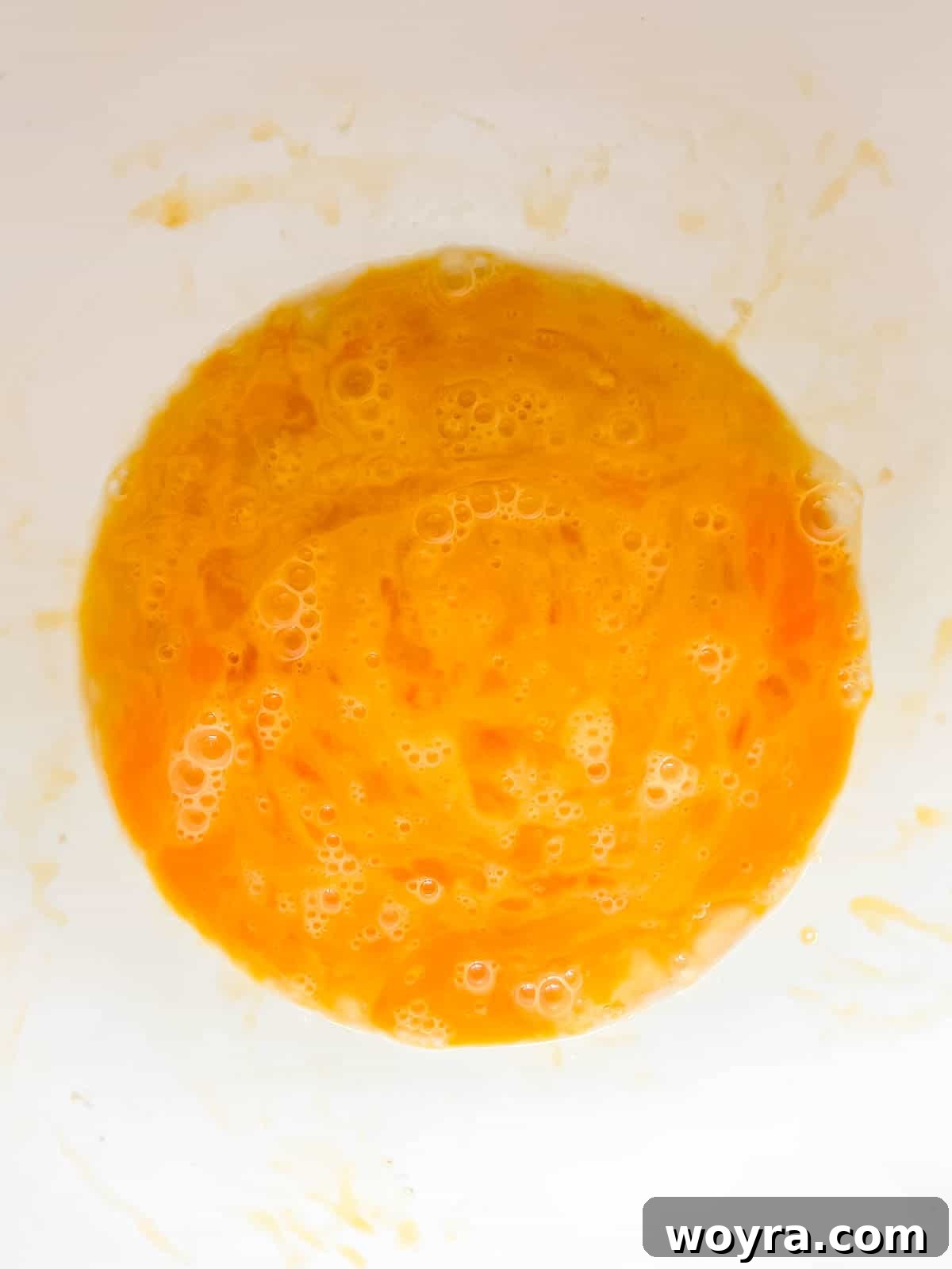 Ten large eggs cracked into a bowl and lightly whisked.