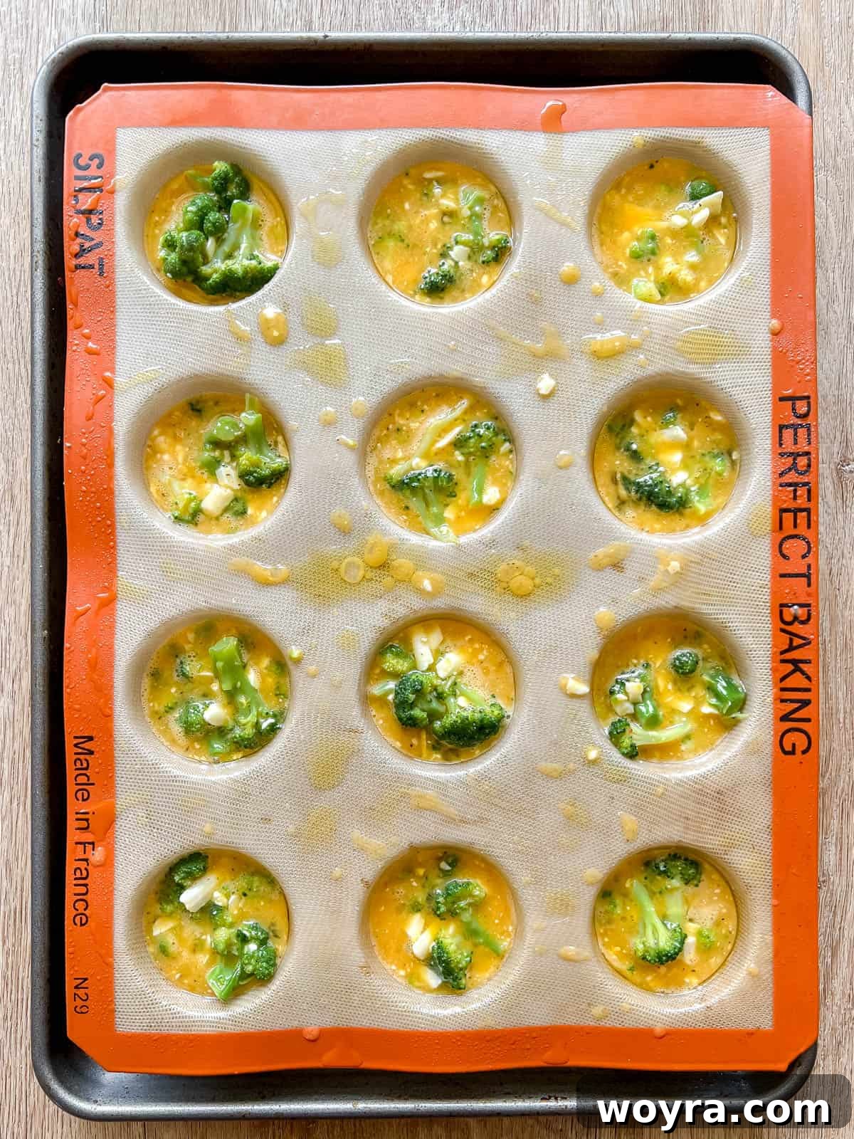 The broccoli egg muffin batter carefully poured into individual muffin tins.