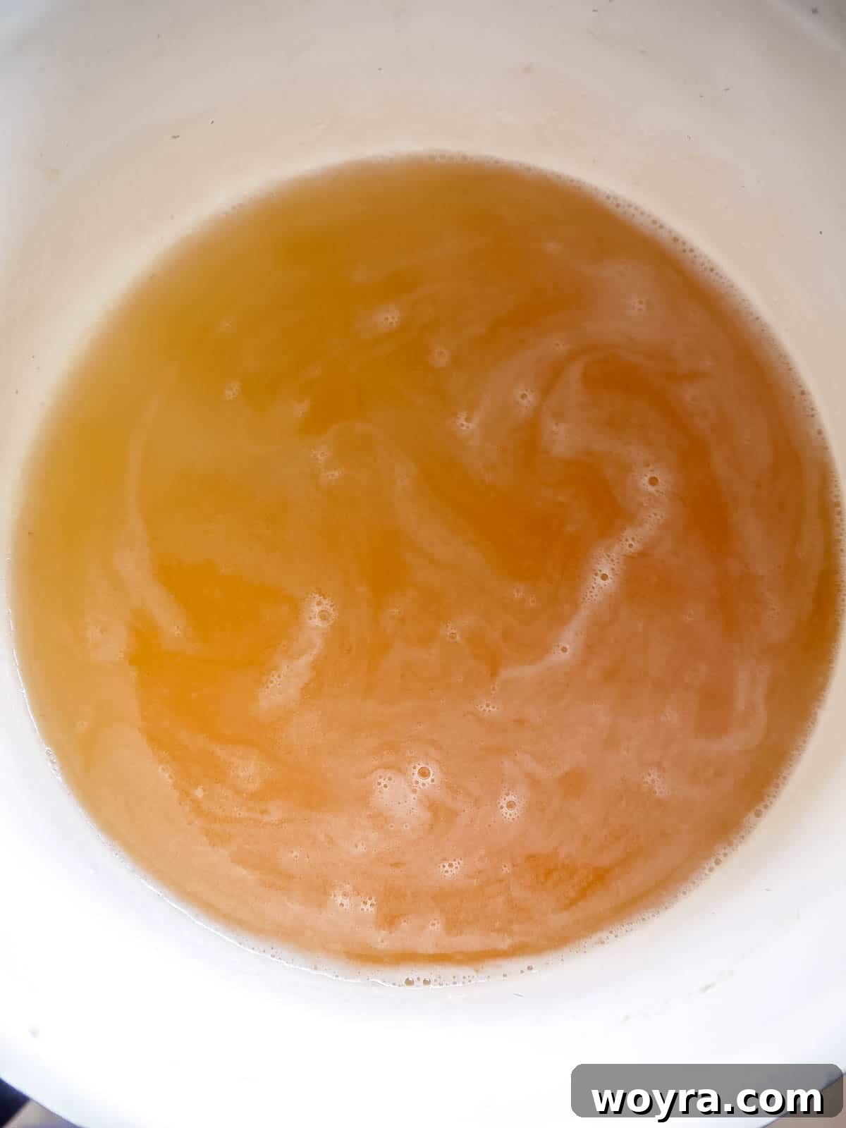 Wholesome Apple Gummy Delights 5 Apple juice and maple syrup heating gently in a saucepan.