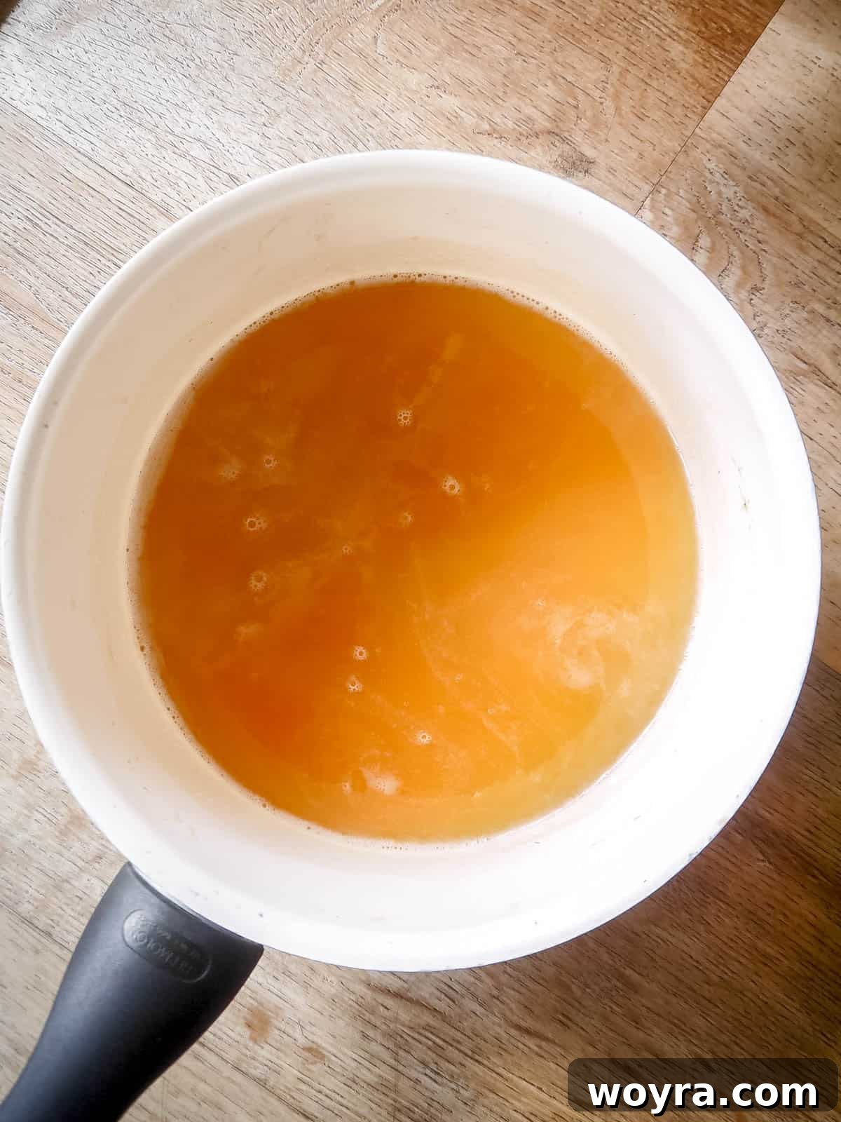 Orchard-Fresh Apple Gummy Bites 6 The bloomed gelatin mixture being stirred into the hot apple juice in a saucepan until completely smooth and dissolved.