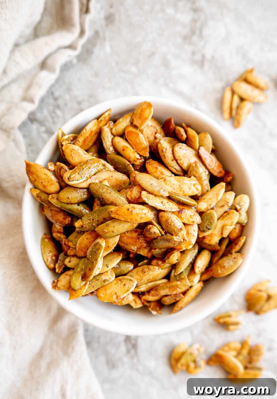 A close-up of golden brown maple roasted pepitas in a rustic ceramic bowl, ready to be enjoyed as a snack or topping.