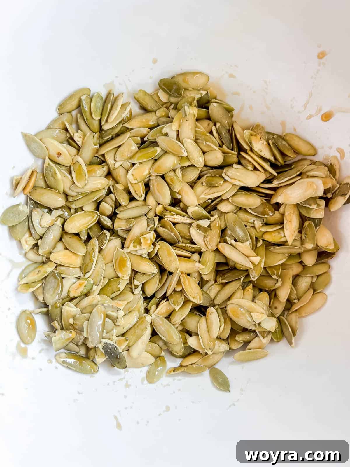Raw green pepitas placed in a mixing bowl, ready for seasoning.