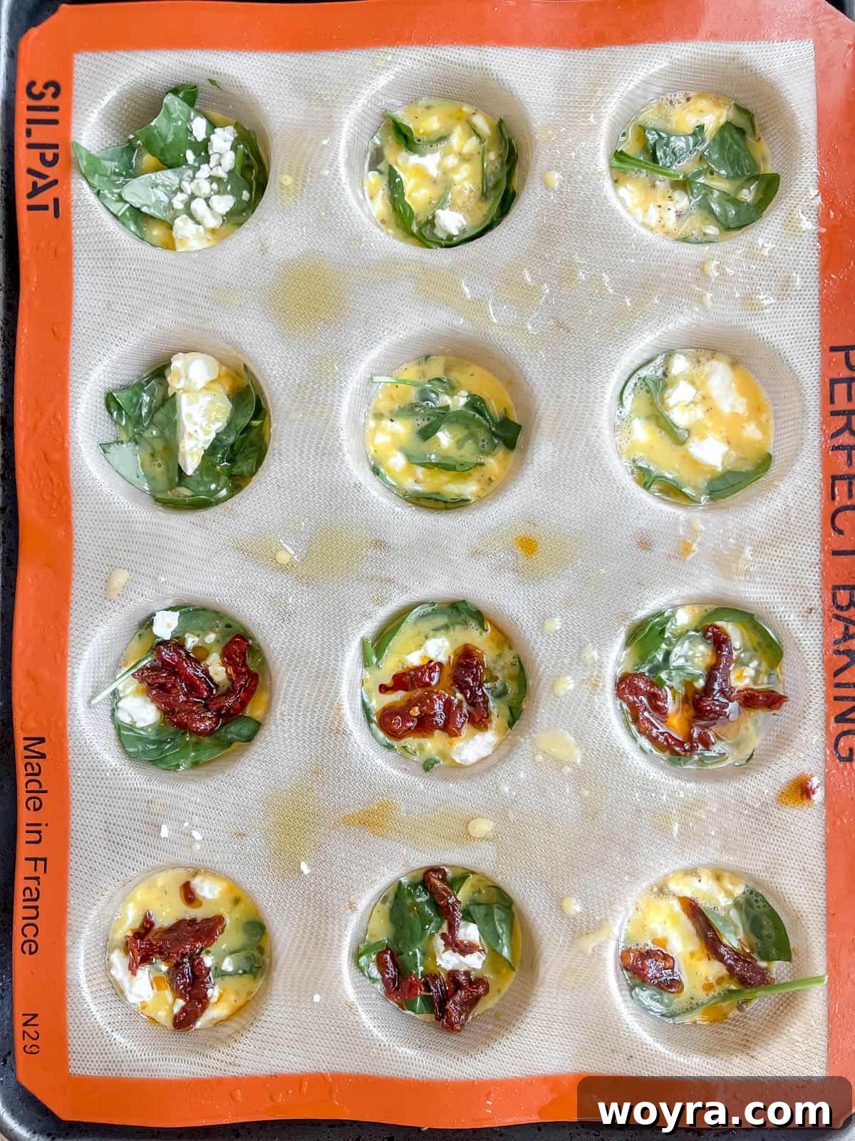 Spinach Feta Egg Bites 8 Egg mixture poured into muffin tins over the spinach, with additional feta on top.