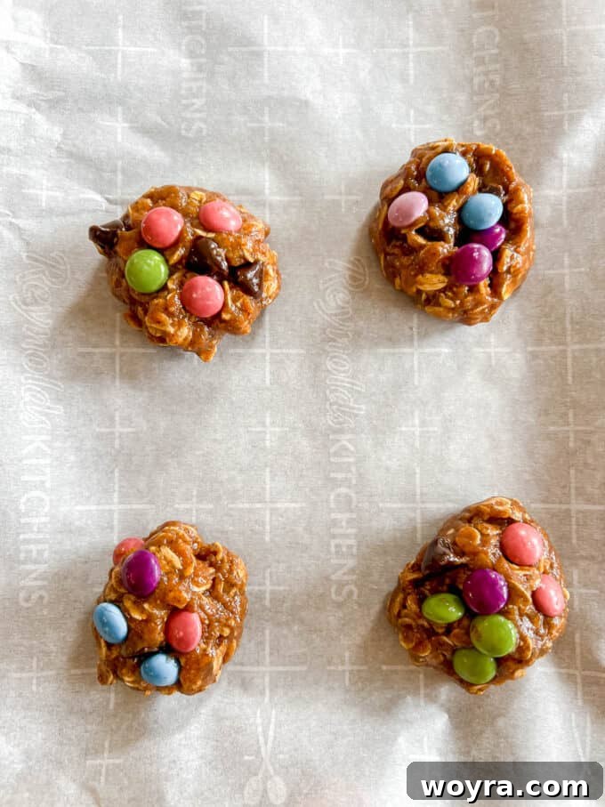 Giant Gluten-Free Flourless Almond Butter Cookies 9 Unbaked flourless monster cookies on a baking sheet, with extra candies pressed on top.
