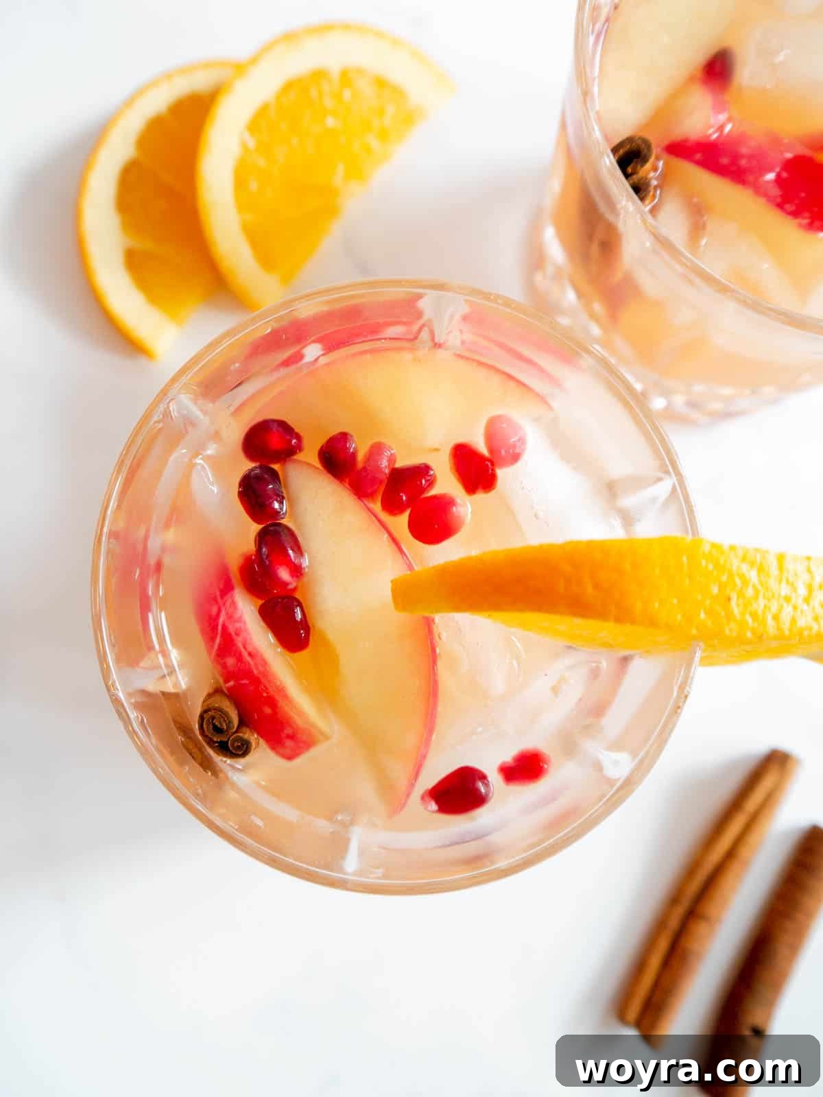 Orchard Ember Elixir 6 An Apple Cider Whiskey Cocktail garnished with pomegranate seeds and citrus slices in a glass.