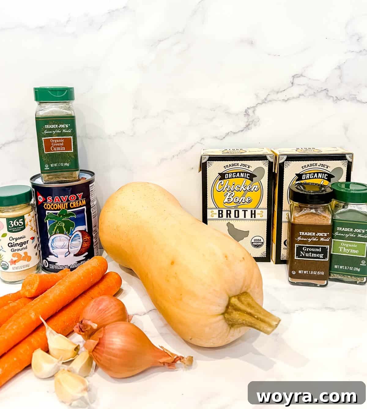 Ingredients needed to make carrot butternut squash soup laid out on a surface.