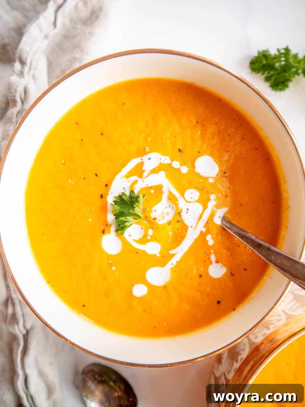 Butternut squash and carrot soup served in a bowl with a drizzle of cream.