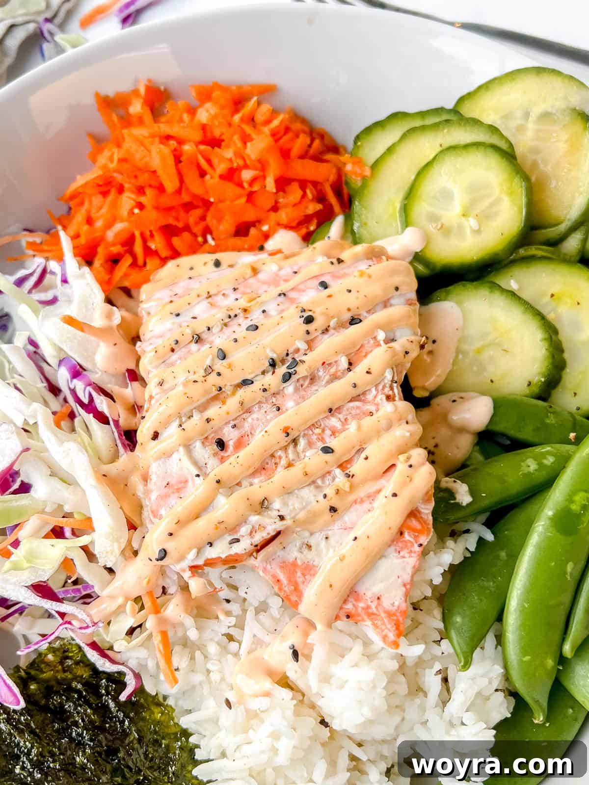 Dynamite Salmon Rice Bowl 2 Fresh salmon rice bowl with spicy mayo on top, garnished with green onions and sesame seeds.