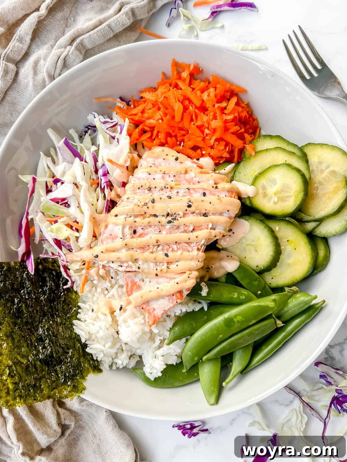 Dynamite Salmon Rice Bowl 11 A beautifully assembled spicy salmon rice bowl on a plate with seaweed sheets.