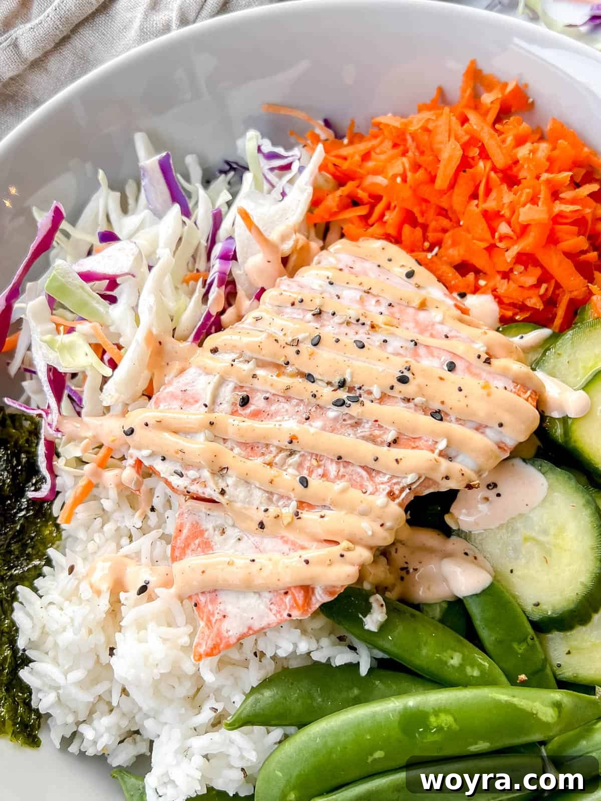 Dynamite Salmon Rice Bowl 12 Close-up of a salmon rice bowl, showcasing the rich colors of salmon, green veggies, and creamy spicy mayo.