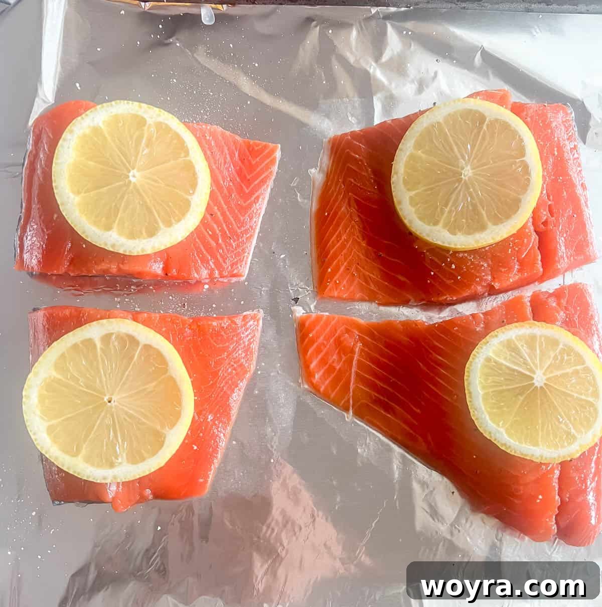 Dynamite Salmon Rice Bowl 8 Raw salmon fillets seasoned with salt, pepper, and lemon slices on aluminum foil.