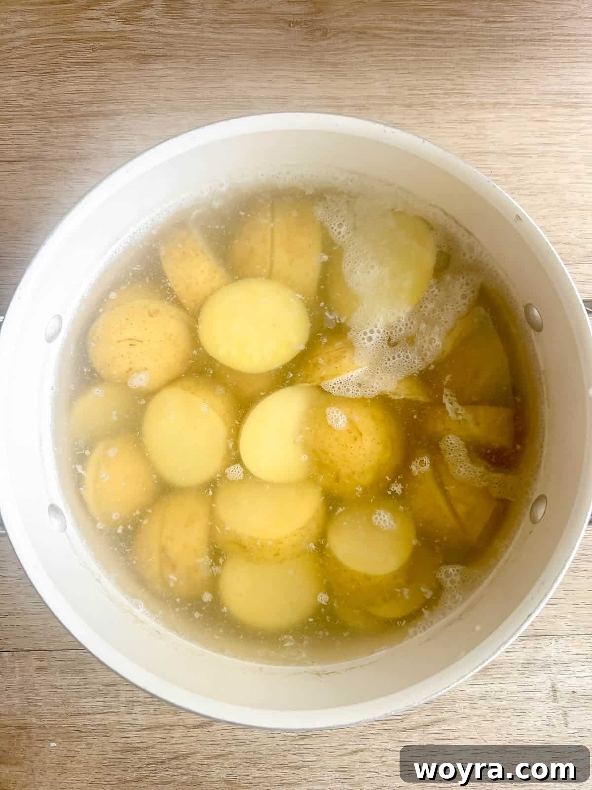 Sliced potatoes boiling in a large pot on the stovetop.
