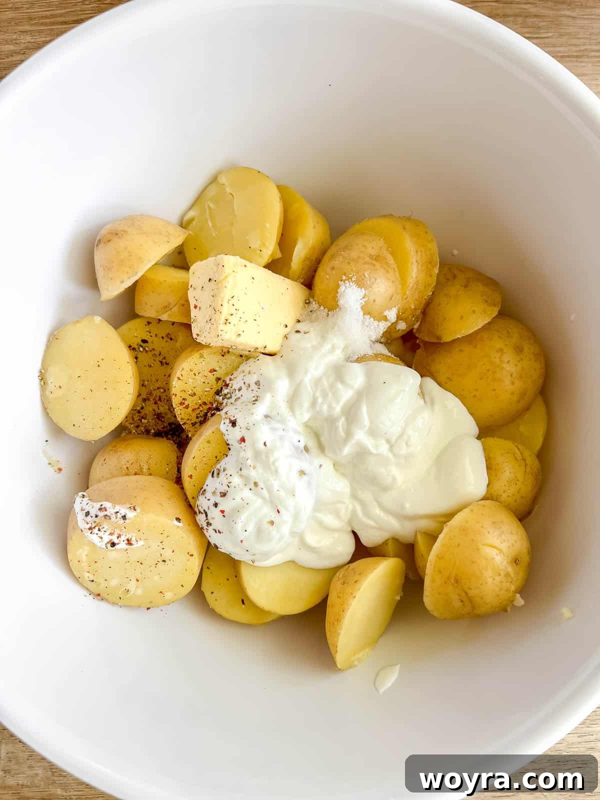 Boiled potatoes in a bowl, topped with Greek yogurt, butter, and milk.