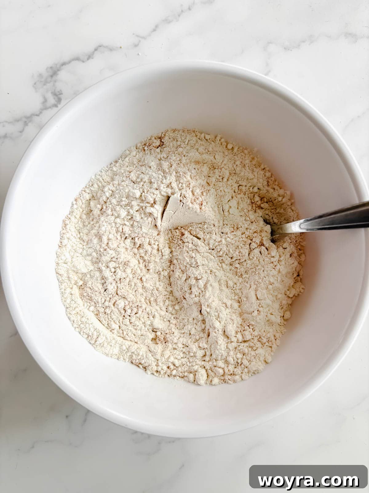 Mediterranean Banana Bread 5 Dry ingredients for olive oil banana bread recipe, including flour, baking soda, and cinnamon, mixed in a separate bowl.