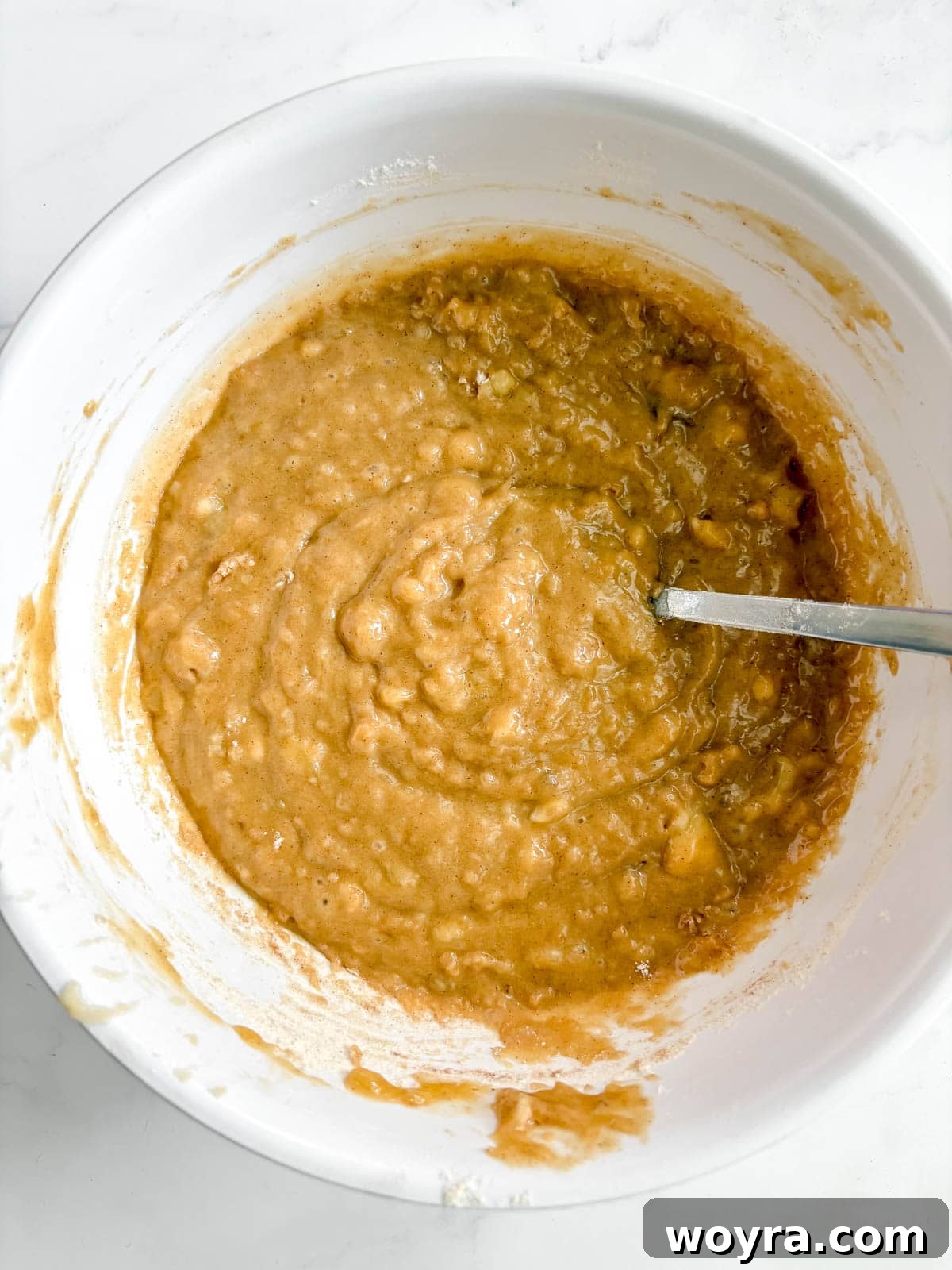 Mediterranean Banana Bread 6 Olive oil banana bread batter being gently mixed in a large bowl, showcasing its smooth consistency.