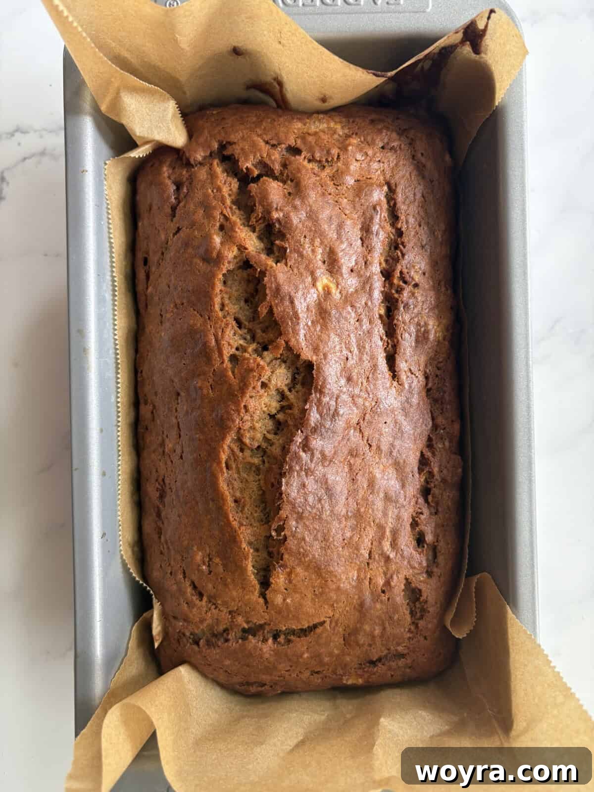 Mediterranean Banana Bread 8 A golden-brown olive oil banana bread loaf, fresh out of the oven, cooling on a rack.