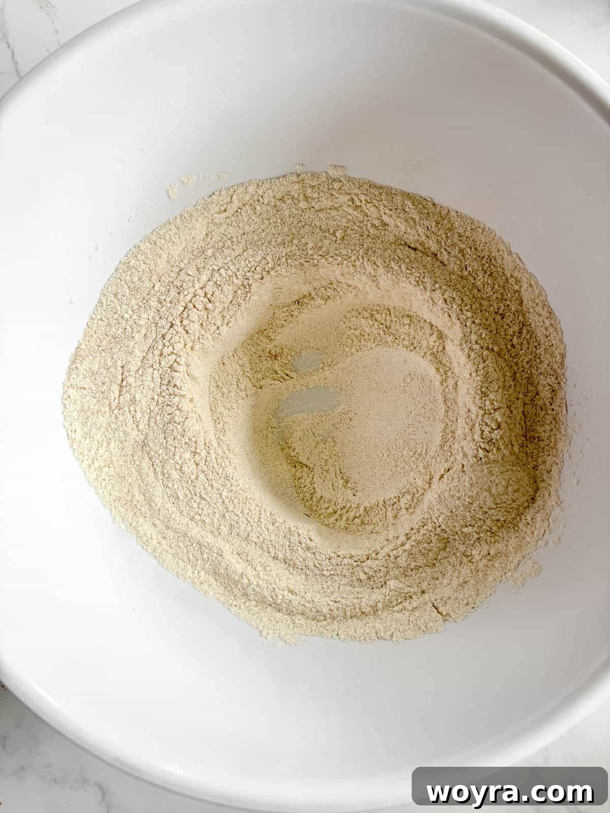 A visible well created in the center of the dry ingredients mixture.