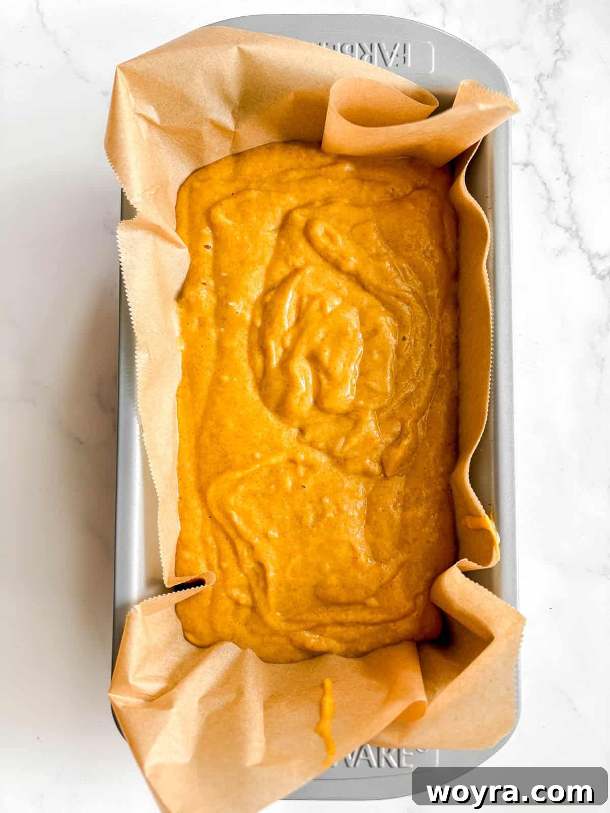 Dairy-free pumpkin bread batter in a lined loaf tin, ready for baking.