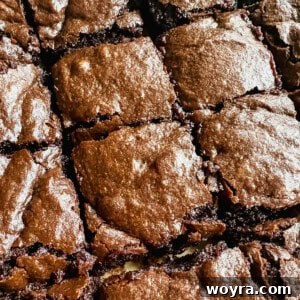 A beautifully baked, rich olive oil brownie with a slight crackle on its glossy top surface, inviting indulgence.
