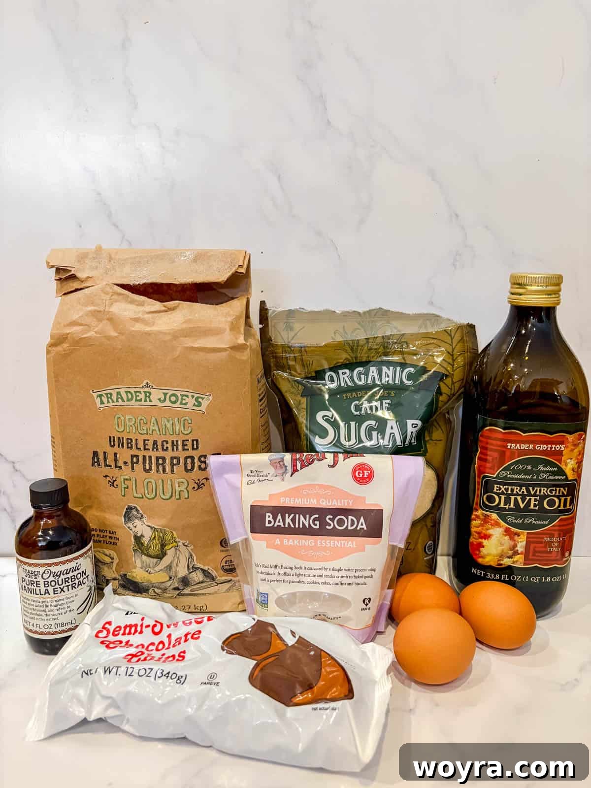 Silky Olive Brownies 3 A curated selection of fresh, high-quality ingredients, including olive oil, chocolate chips, eggs, and flour, neatly arranged on a rustic wooden surface, ready for baking.