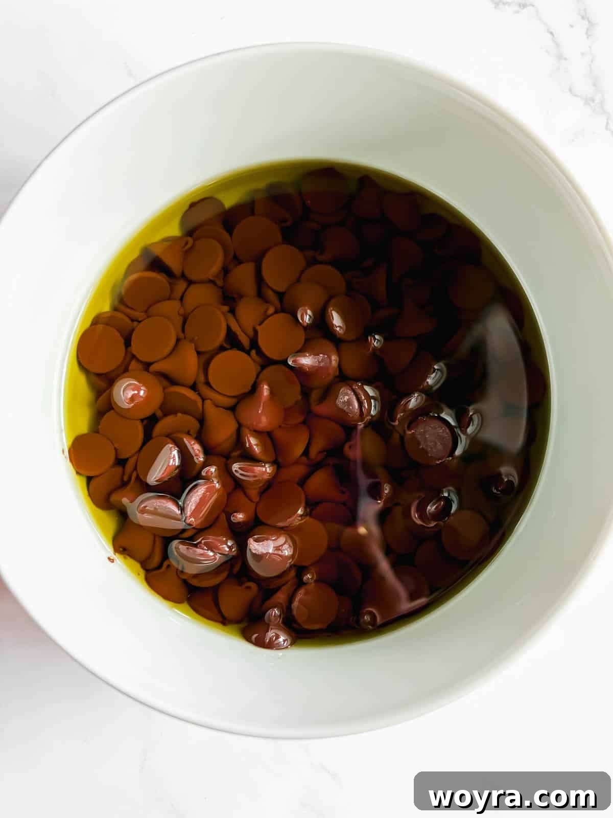 Silky Olive Brownies 4 Semi-sweet chocolate chips melting perfectly into rich olive oil in a heatproof bowl, forming a smooth, glossy mixture.