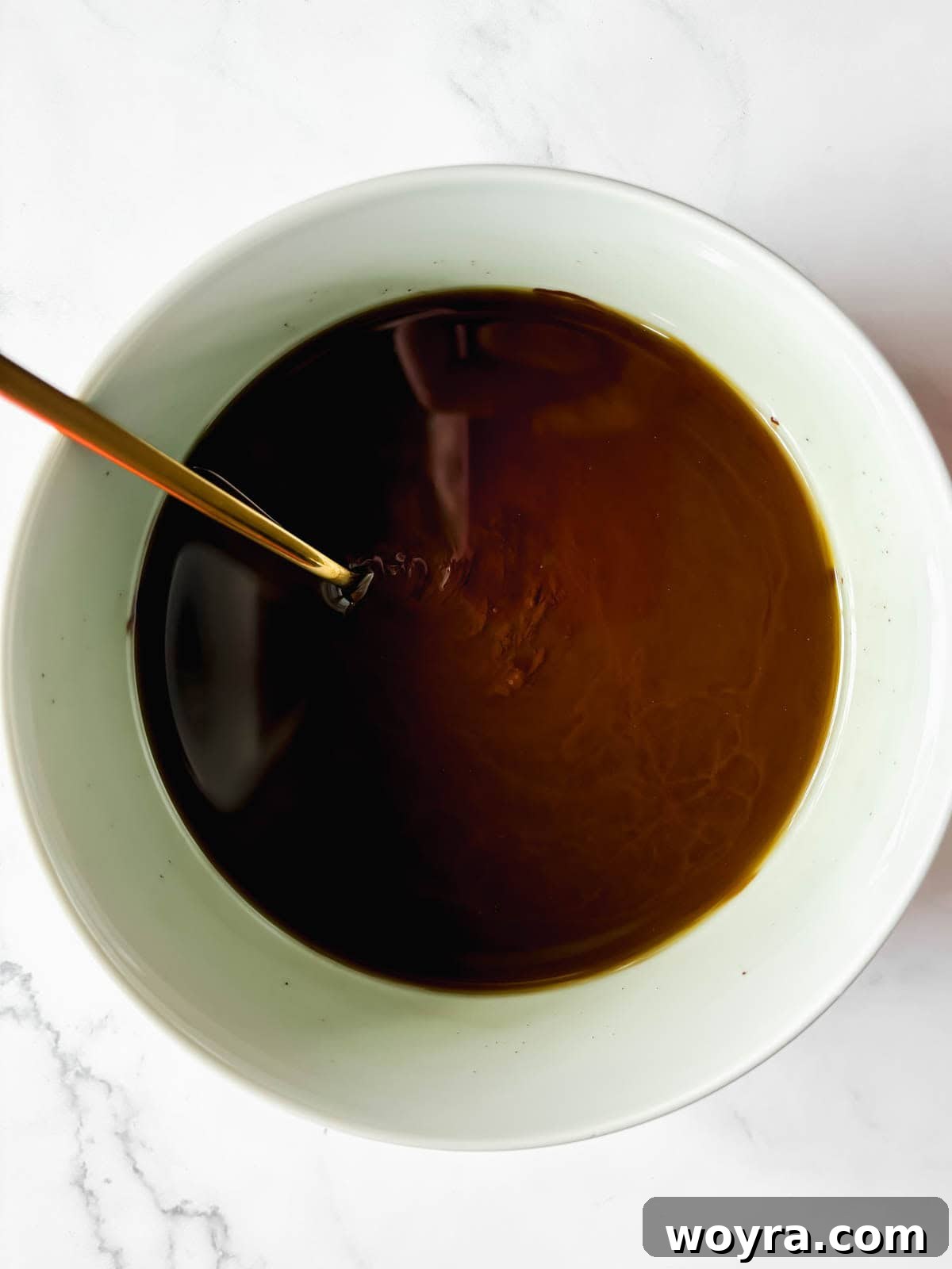 Silky Olive Brownies 5 Granulated sugar and fragrant vanilla extract being expertly stirred into the warm, melted chocolate and olive oil mixture, creating a harmonious blend.