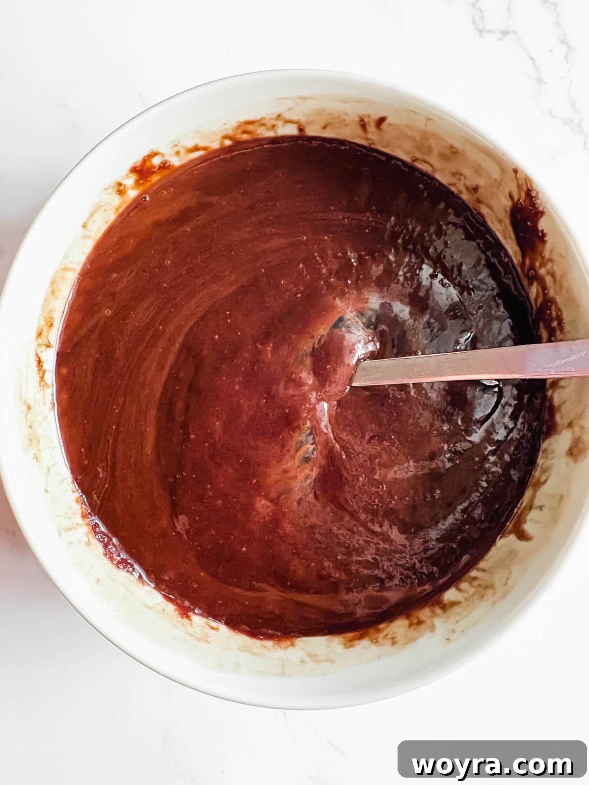 Silky Olive Brownies 6 Three fresh eggs being gently whisked into the rich brownie batter, one by one, ensuring smooth emulsification.