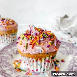 A small batch funfetti cupcake on a white plate, showcasing its colorful interior and creamy frosting.