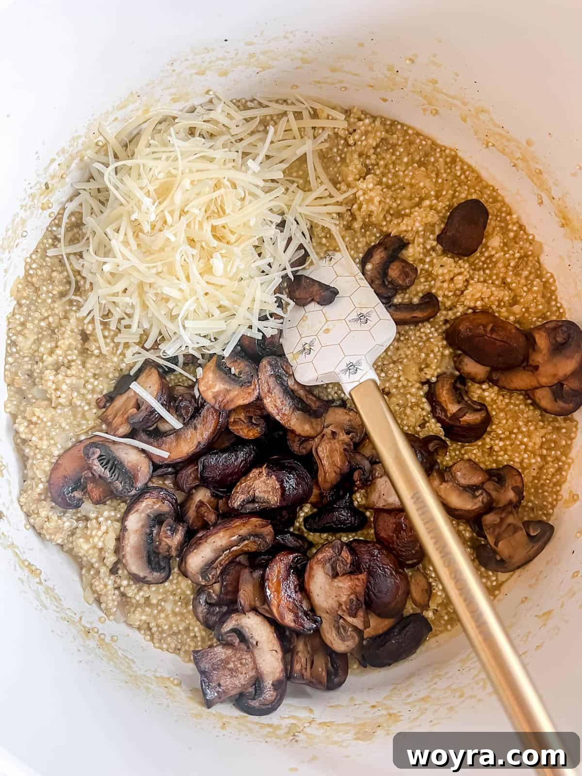 Velvety Mushroom Quinoa Risotto 12 Cooked mushrooms and Parmesan cheese being stirred into the creamy quinoa risotto in a large pan.