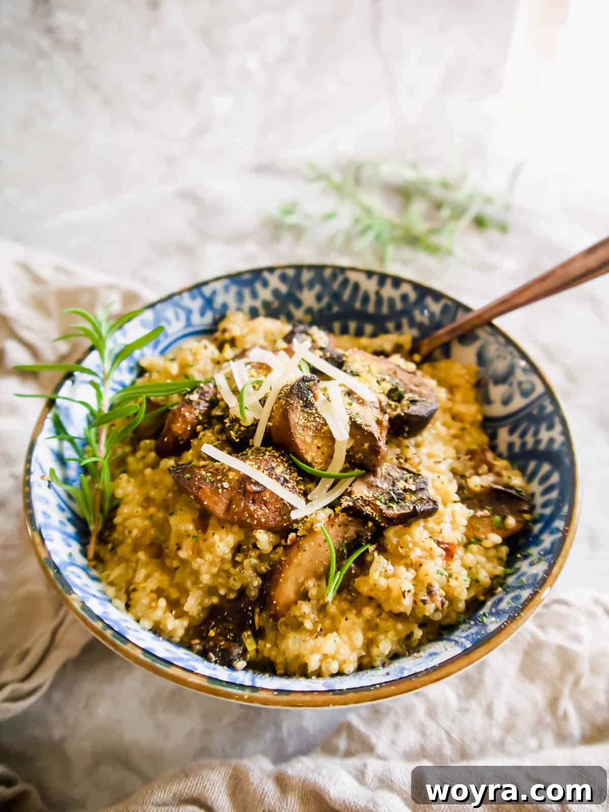A close-up of a bowl of creamy quinoa mushroom risotto with a spoon, highlighting its inviting texture.
