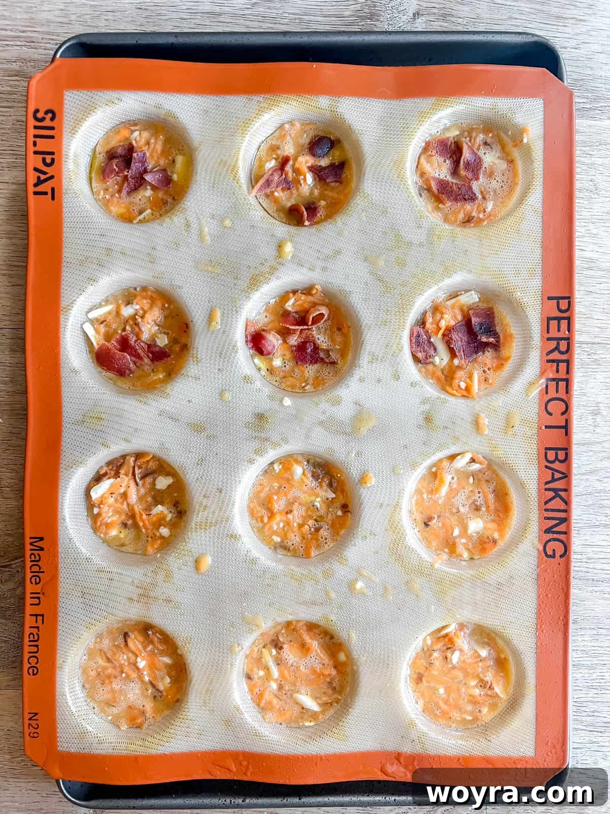 Sweet Potato Bacon Breakfast Nests 7 Sweet potato egg cups in a silicone muffin tin, topped with crumbled bacon before baking.