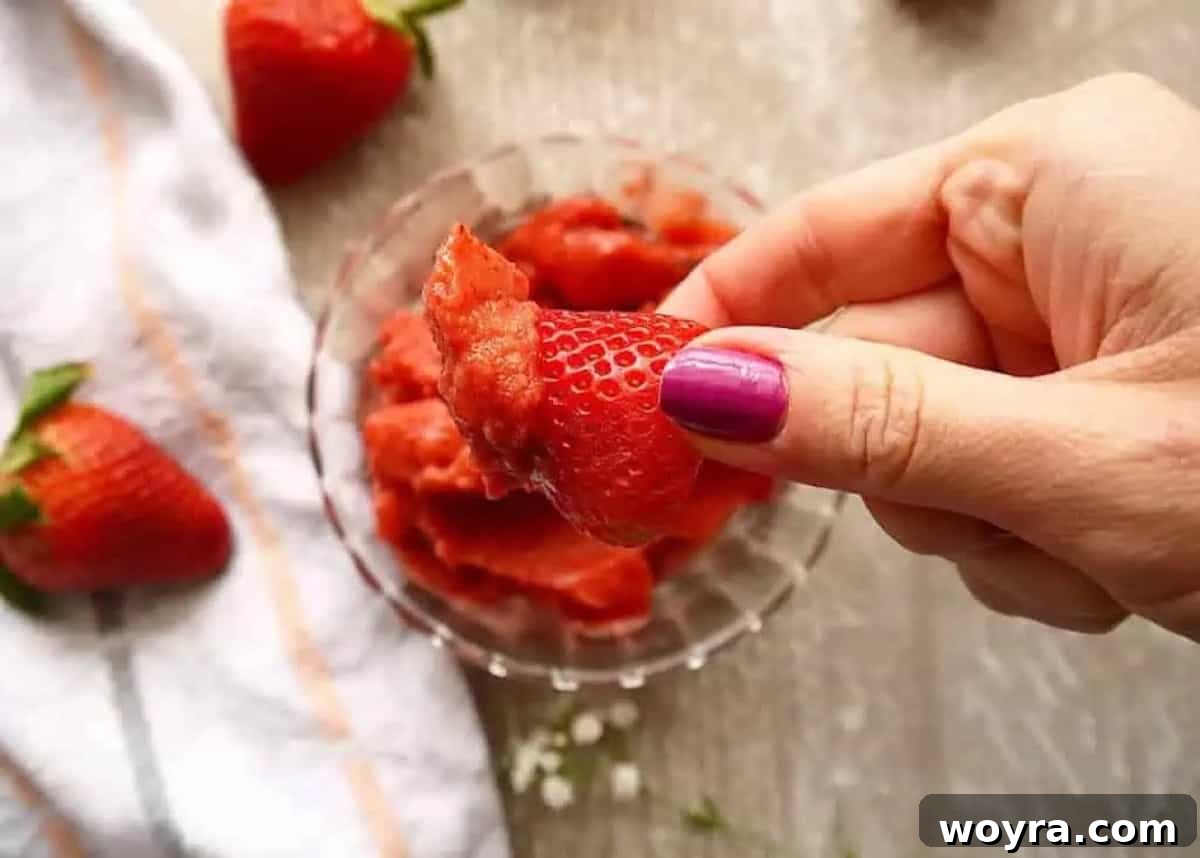Strawberry Mango Blender Sorbet 5 A fresh strawberry being dipped into a swirl of homemade strawberry mango sorbet, highlighting its smooth texture.